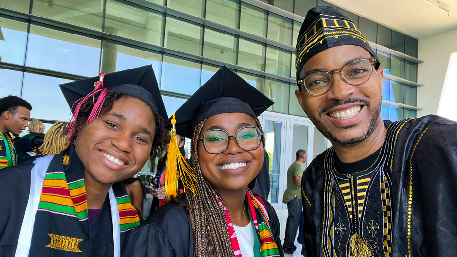 African university graduates in caps, gowns and kente stoles celebrating at graduation